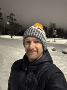 A man in a woolly hat in the snow